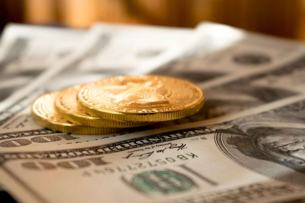 three round gold-colored coins on 100 US dollar banknotes