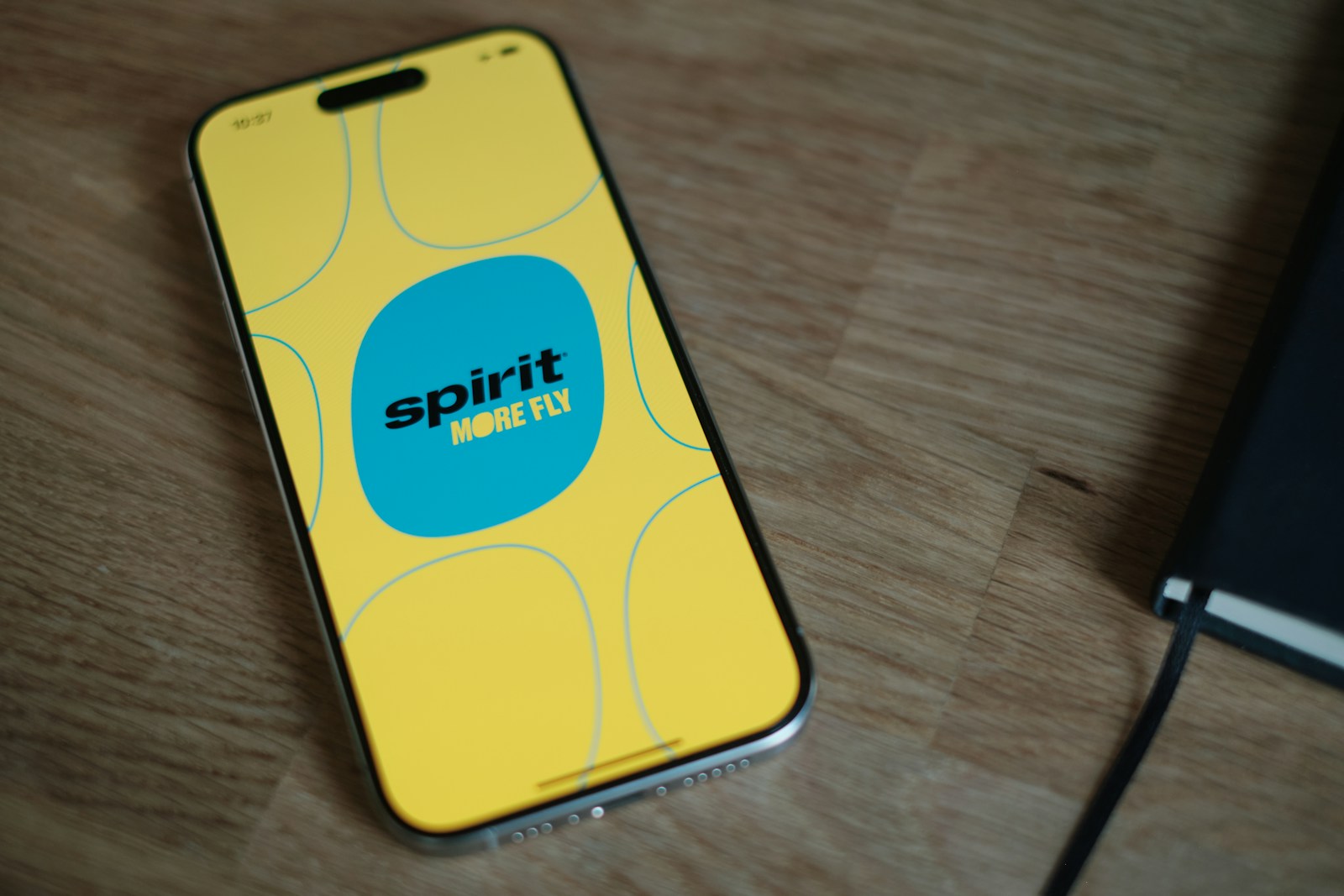 A cell phone sitting on top of a wooden table with spirit airlines app